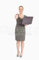 Woman holding a laptop while she is thump up