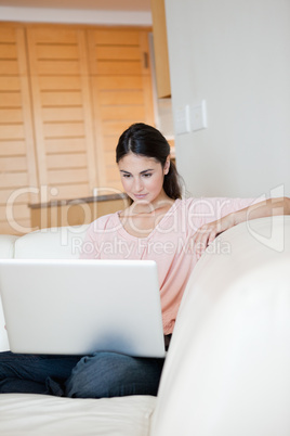 Woman using a laptop while sitting on a sofa