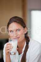 Woman drinking a glass of milk while looking the camera