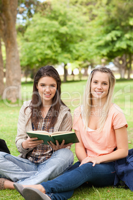 Portrait of female teenagers sitting with a textbook