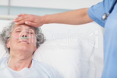 Nurse putting her hand on the forehead of a patient