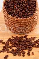 Close up of a basket filled with coffee seeds on a wooden tablec