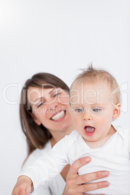 Smiling mother holding her surprised baby