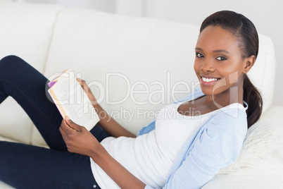 Black woman looking at camera while holding a book