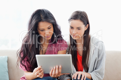 Two women on the couch looking at a tablet together