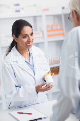 Pharmacist showing a drug box to a old man