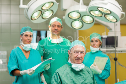 Smiling surgeon sitting with a team behind him