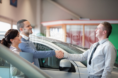 Salesman smiling while shaking the hand of a customer