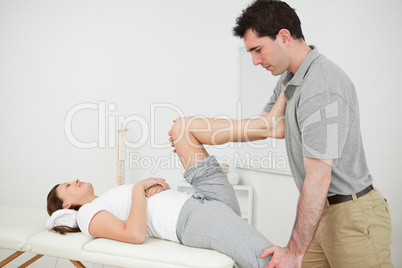 Chiropractor stretching the legs of his patient while standing