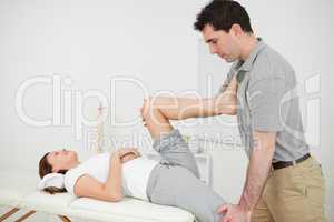 Chiropractor stretching the legs of his patient while standing