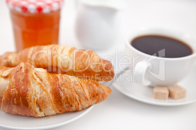 Croissants and a cup of coffee on white plates with sugar milk a