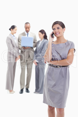 Businesswoman looking up on the phone with co-workers in the bac