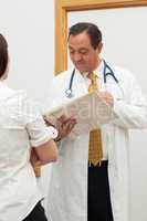 Doctor looking into a file while talking to a woman