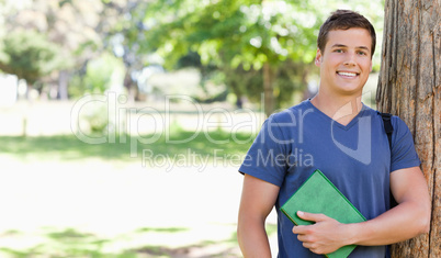 Portrait of a smiling muscled student holding a textbook