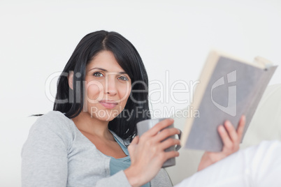 Woman holding a grey mug and a book