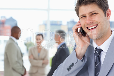 Young manager laughing while using his mobile phone