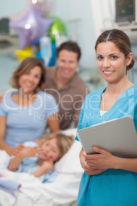 Nurse looking at camera next to a family