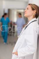 Doctor with her hands in her pockets against a wall