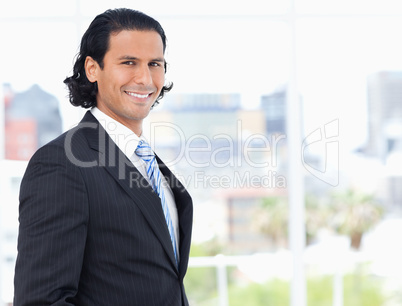 Young executive proudly standing in front of a window