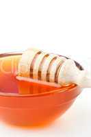 Honey dipper honrizontally on the edge of the bowl
