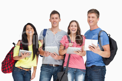 A group of students with tablets and backpacks smiling and looki