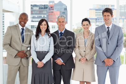 Smiling business team standing upright side by side with their h