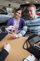 Happy couple receiving keys from a salesman