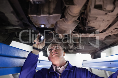 Concentrated mechanic illuminating a car with a flashlight