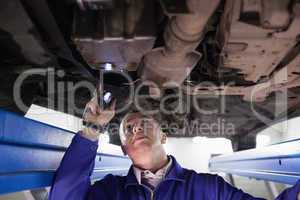 Concentrated mechanic illuminating a car with a flashlight