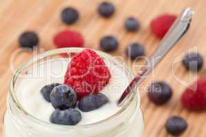 Close up of a pot yoghurt with blueberries and raspberry