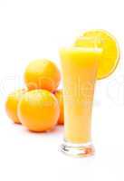 Pile of oranges behind a glass of orange juice