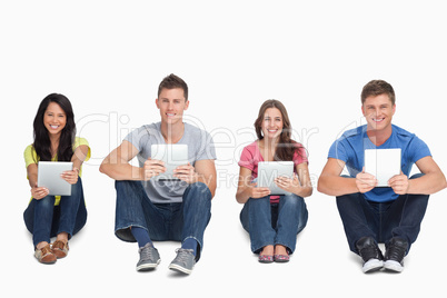 A group of people holding tablets as they look at the camera