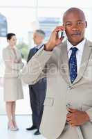 Young manager talking on the phone very seriously while his team