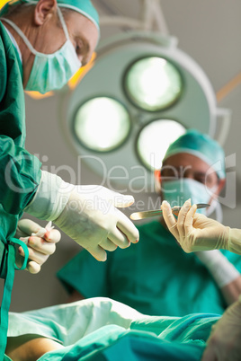 Surgeon taking a scalpel from a gloved hand