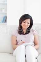 Woman writing on a notebook while sitting on a couch
