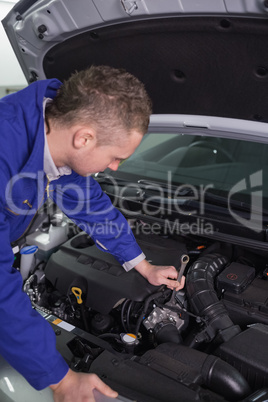 Mechanic repairing an engine with a spanner