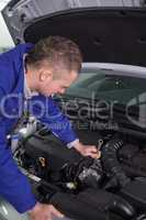 Mechanic repairing an engine with a spanner