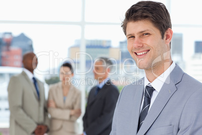 Smiling businessman standing upright with his team between him