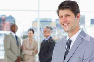 Smiling businessman standing upright with his team between him