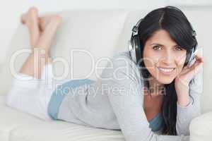 Woman smiling with headphones on while lying on a sofa