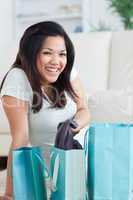 Smiling woman taking clothes off from a shopping bag