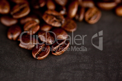 Dark blurred coffee seeds laid out together on a black table