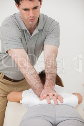 Woman lying forward while a physiotherapist massaging her back