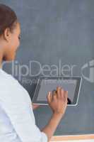 Woman using a tablet computer next to a blackboard