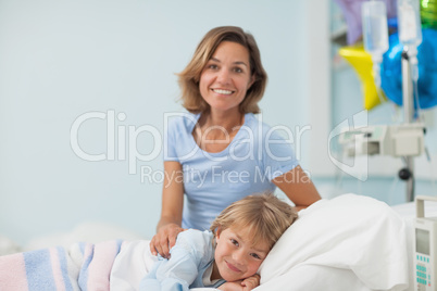 Child lying on a medical bed next to his mother