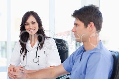 Young nurse sitting at the desk looking at her co-worker