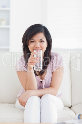 Woman drinking water while sitting in a couch