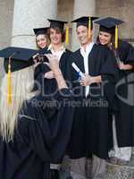 Blonde graduate taking a picture of her friend