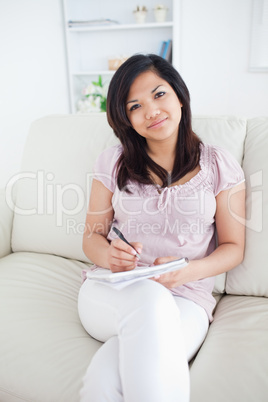 Woman holding a notebook while sitting in a couch