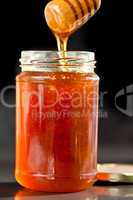 Honey sticky trickle dropping in a jar